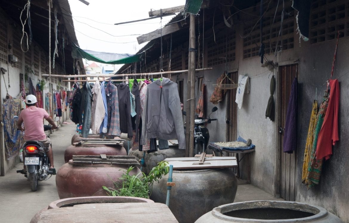 Motorcyclists in a very narrow street blocked with clothes and pots
