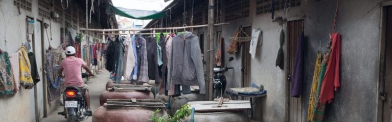 Motocycliste dans une rue très étroite et bloquée avec des vêtements et des casseroles