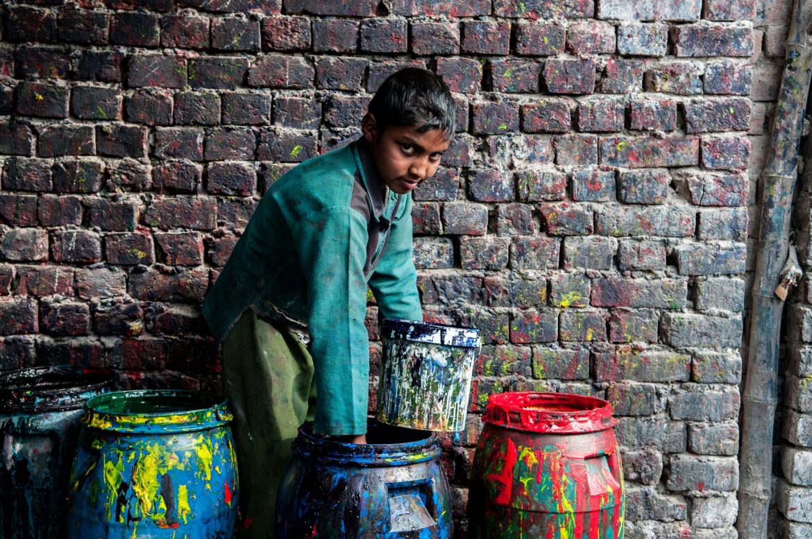 Un garçon pakistanais manipule des seaux de peinture