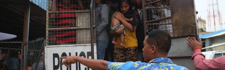 Thailand-Deportation-MigrantInnen-JohnHume Migrant*innen werden von der Polizei in einen Polizeiwagen eingepfercht, darunter eine junge Frau mit Baby.